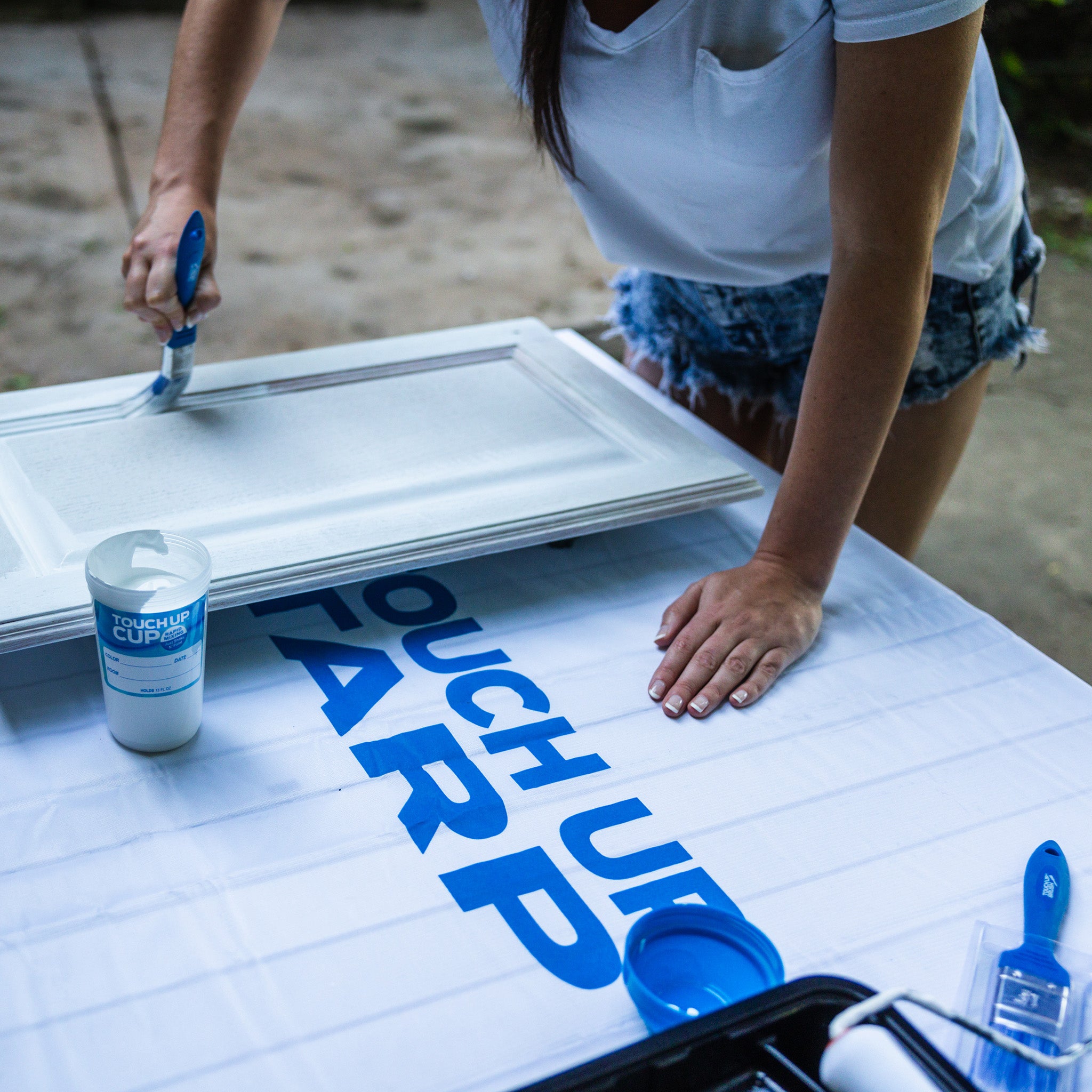 Woman using Touch Up painters tarp to protect table for painting project