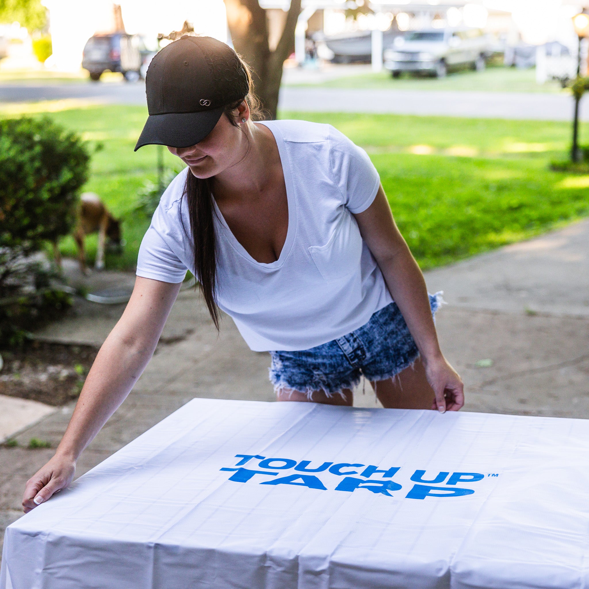 Woman spreading Touch Up painters drop cloth onto table to prepare for painting project.